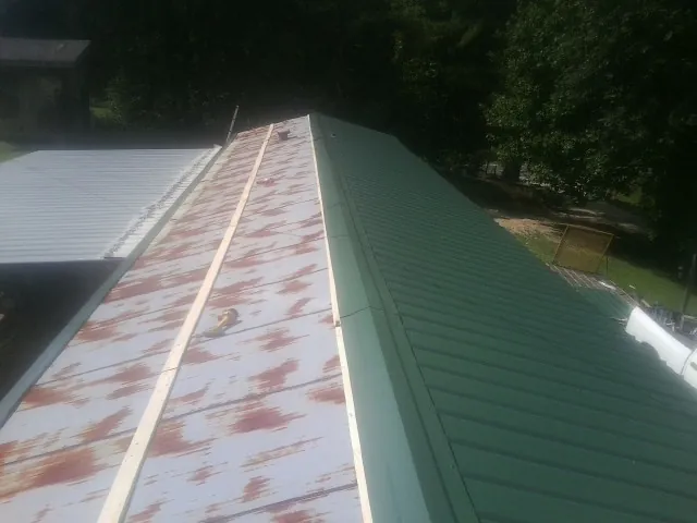 Old rusted panels beside newly installed green metal roofing — Wind Damage Roof Repair by Roofing Brothers in Freeburg
