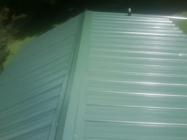 New green metal panels meeting at the ridge of a roof — Flat Roof Repair work by our crew in Freeburg