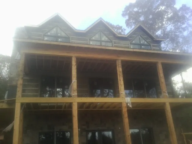 Dormers and porch framing on a large log home under construction — Roof Coating work by our crew in Freeburg