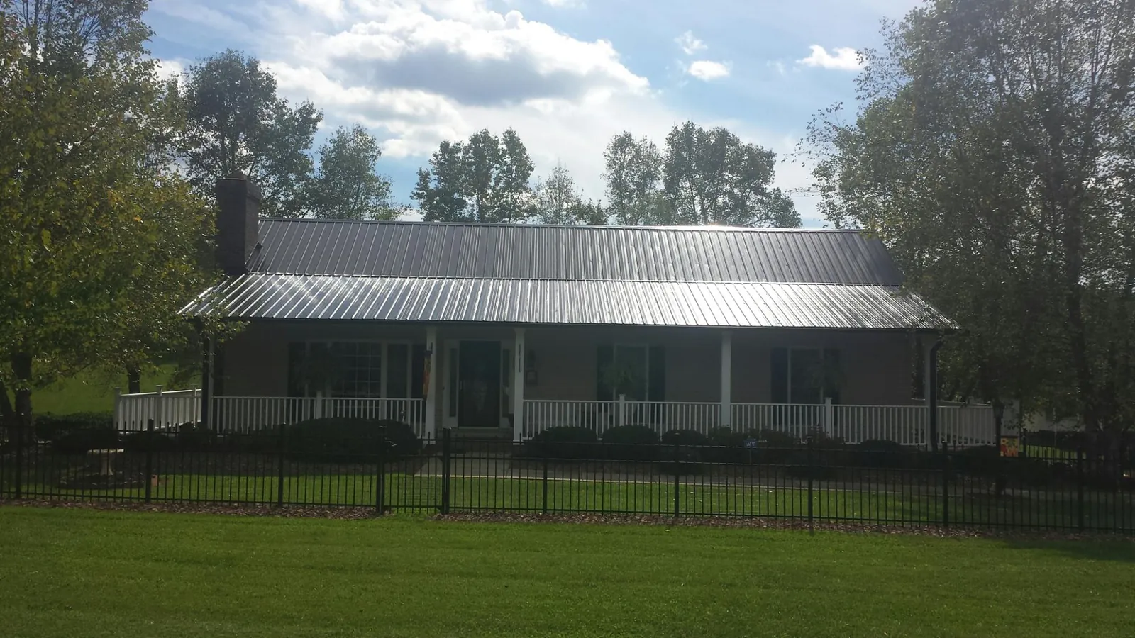 Gray metal roof on a brick ranch with a full width front porch — Gutter Guard Installation work by our crew in Freeburg