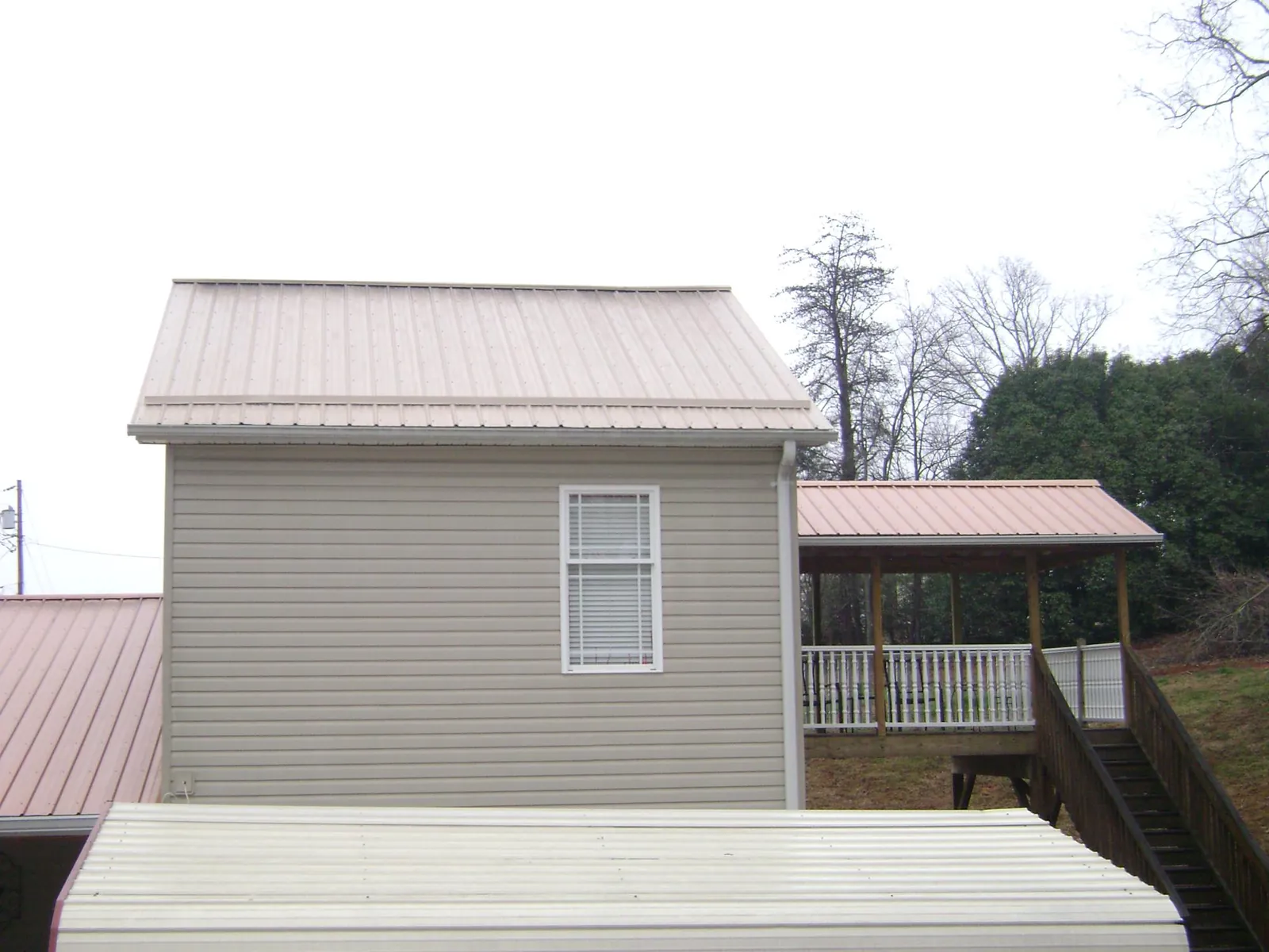 Tan metal roofs on a two story addition and attached porch, from a Roof Replacement job in Freeburg