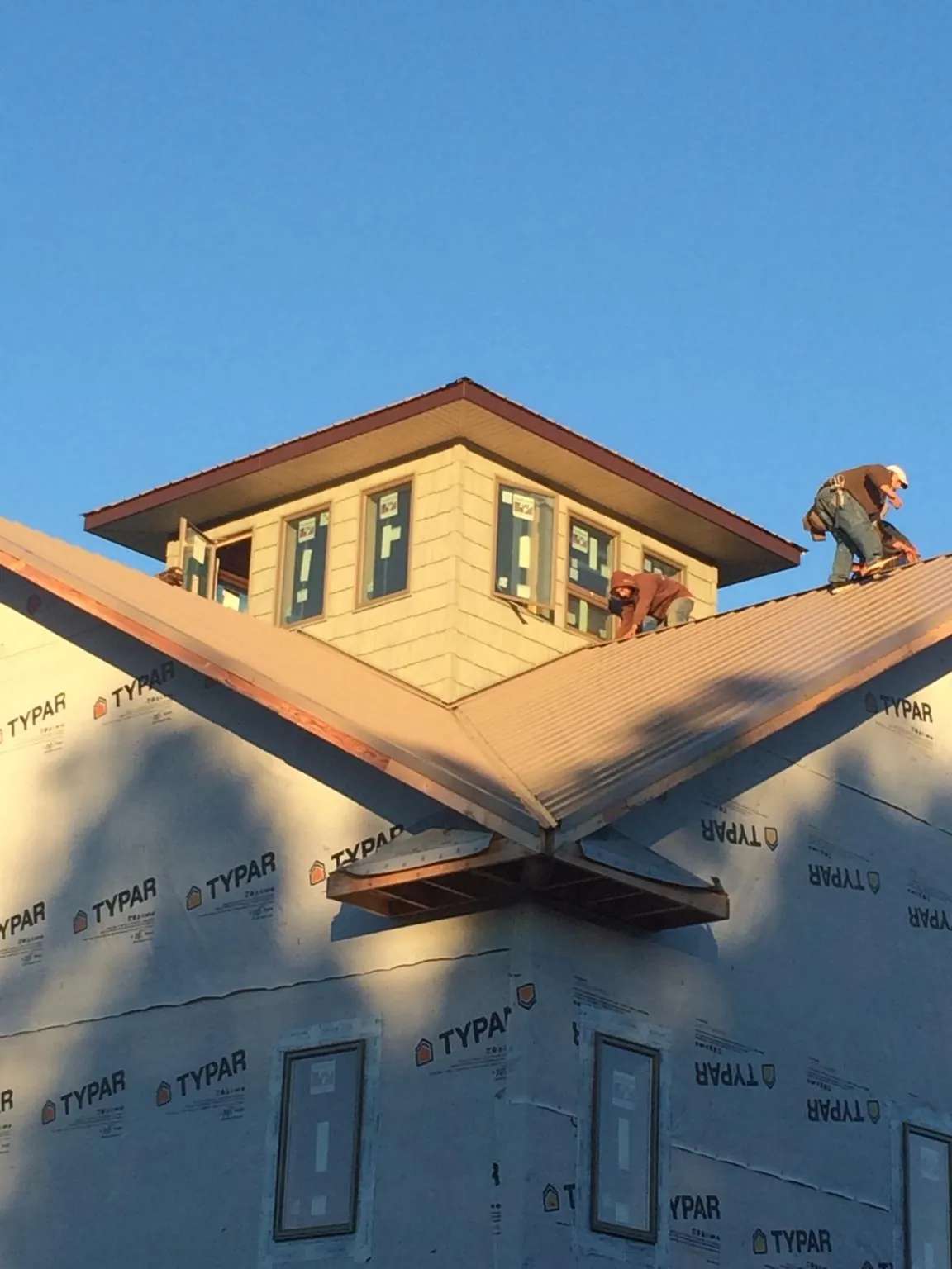 Roofers working around a rooftop cupola on a new metal roof at sunset — Roof Waterproofing in Freeburg by Roofing Brothers